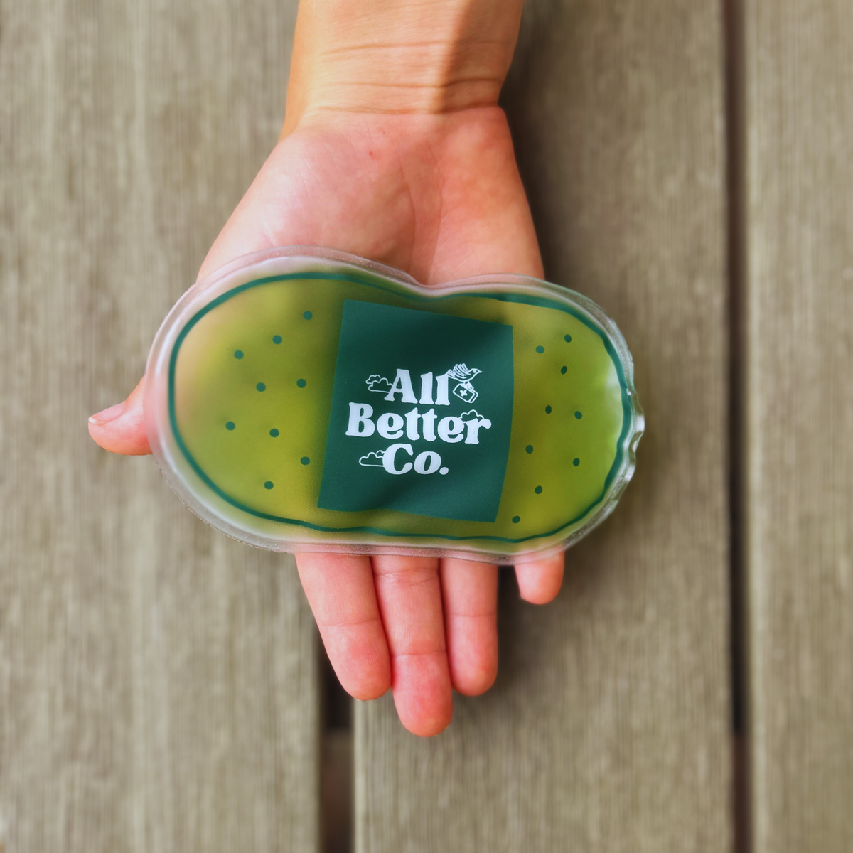 hand holding all better chill pack on wood surface.