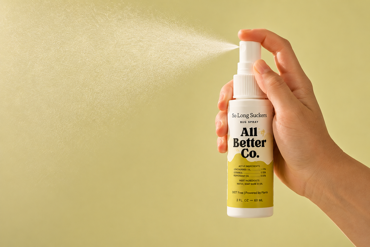 Hand holding a spray bottle labeled 'All Better Co.' against a yellow background