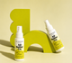 Two bottles of All Better Co. product on a yellow background with a green abstract sculpture.